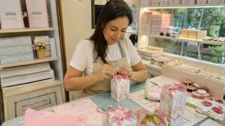 artesã montando lembrancinhas personalizadas em ateliê com caixinhas e fitas